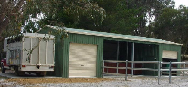 Stables in a yard with a horse van nearby